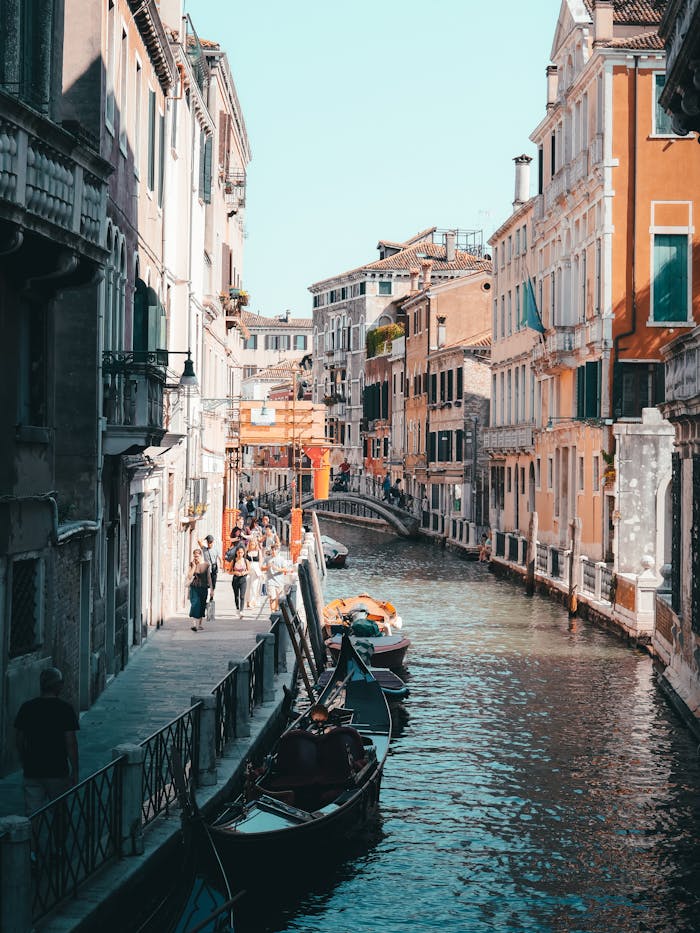 services-03 A bustling canal in Venice with colorful buildings, gondolas, and tourists enjoying a sunny day.