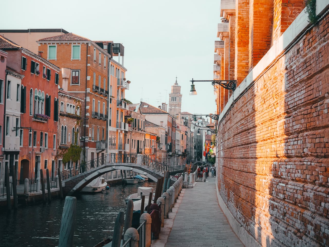 hero-img-01 Charming view of a canal in Venice with colorful buildings and a bridge.