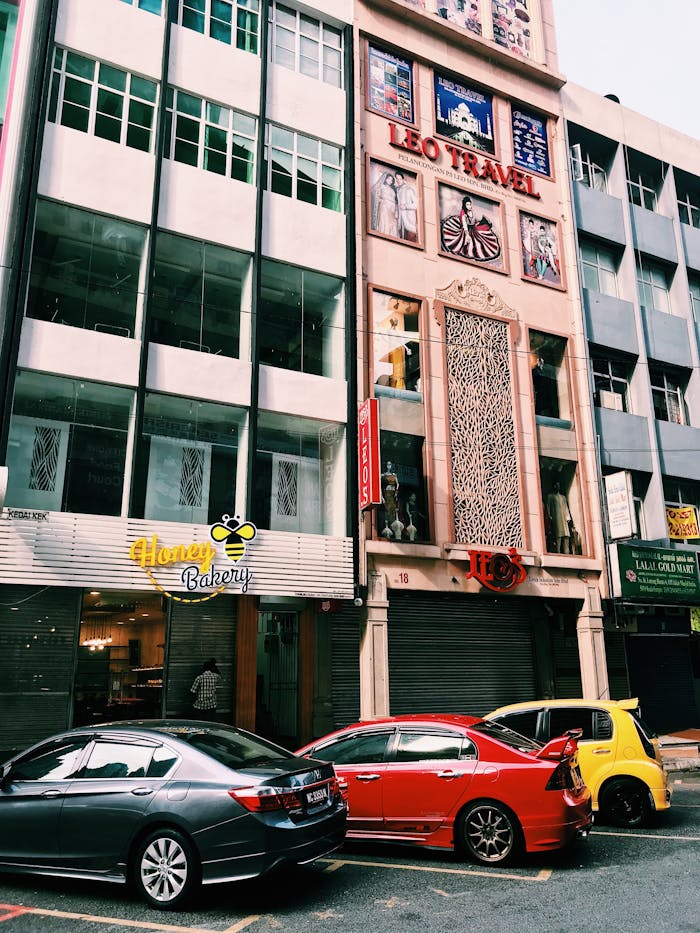 about-01 Lively street in Kuala Lumpur, Malaysia with colorful cars parked by shops.